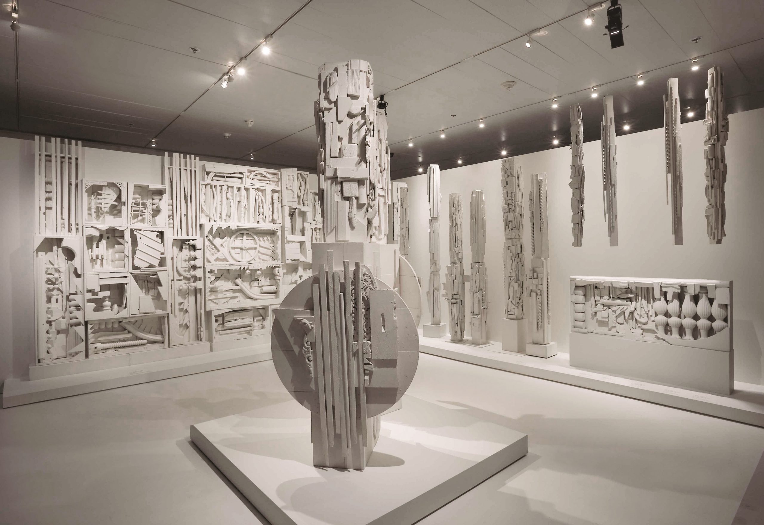 A gallery filled with sculptural elements assembled from various pieces of wood, all painted white.